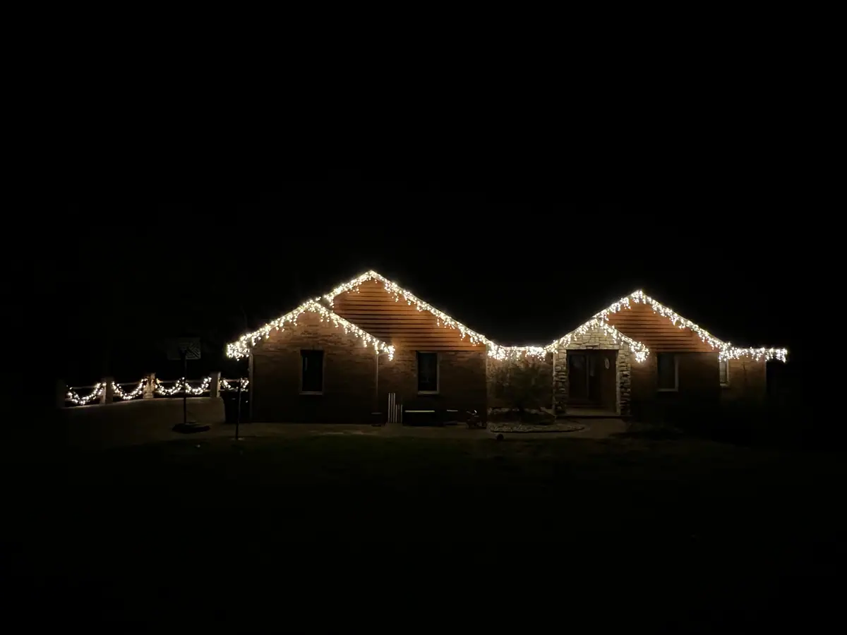 A single-story ranch home traced in warm white C9 lights along the roofline and porch
