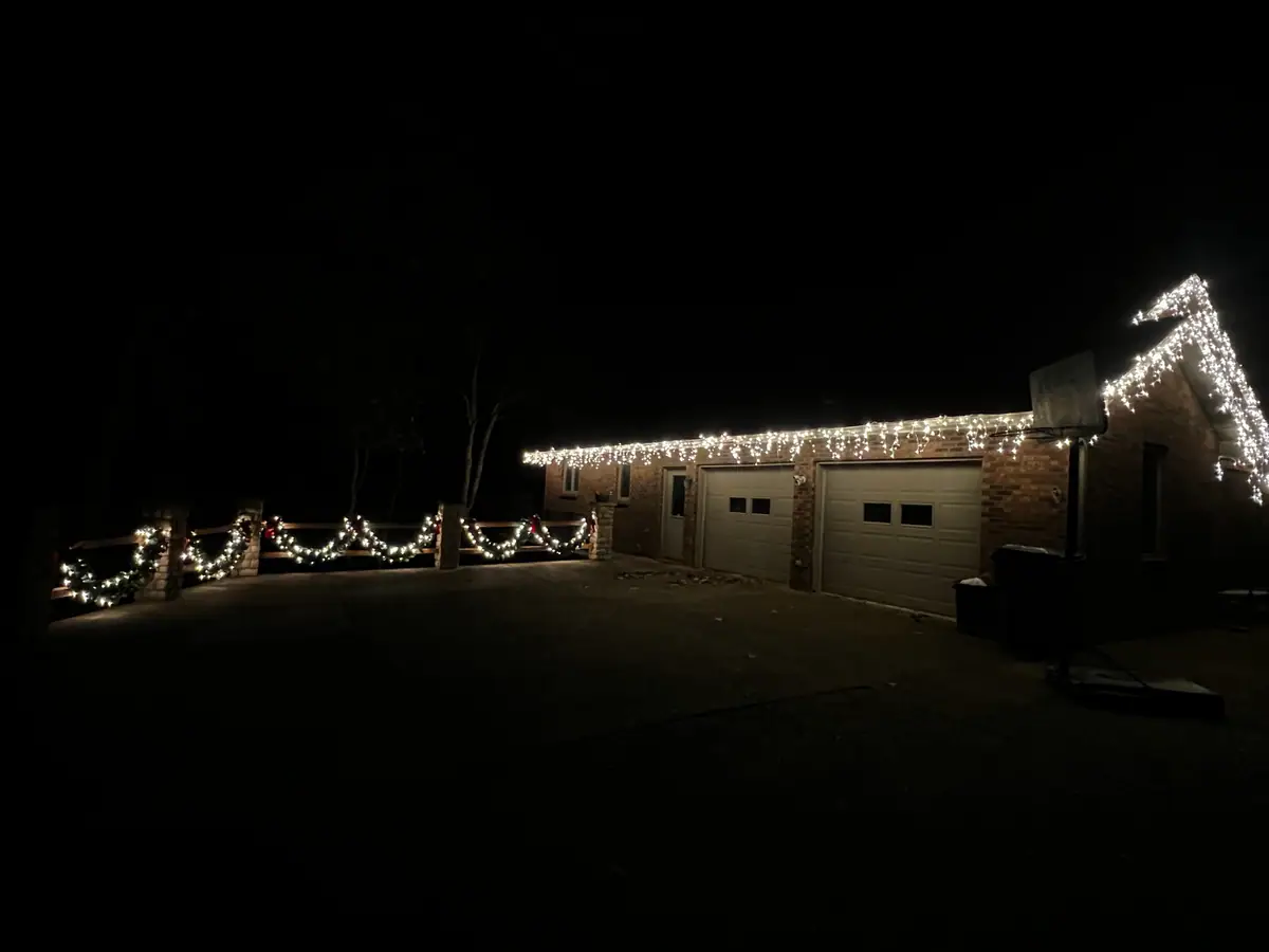 A long outbuilding and garage bays trimmed end to end in warm white lights